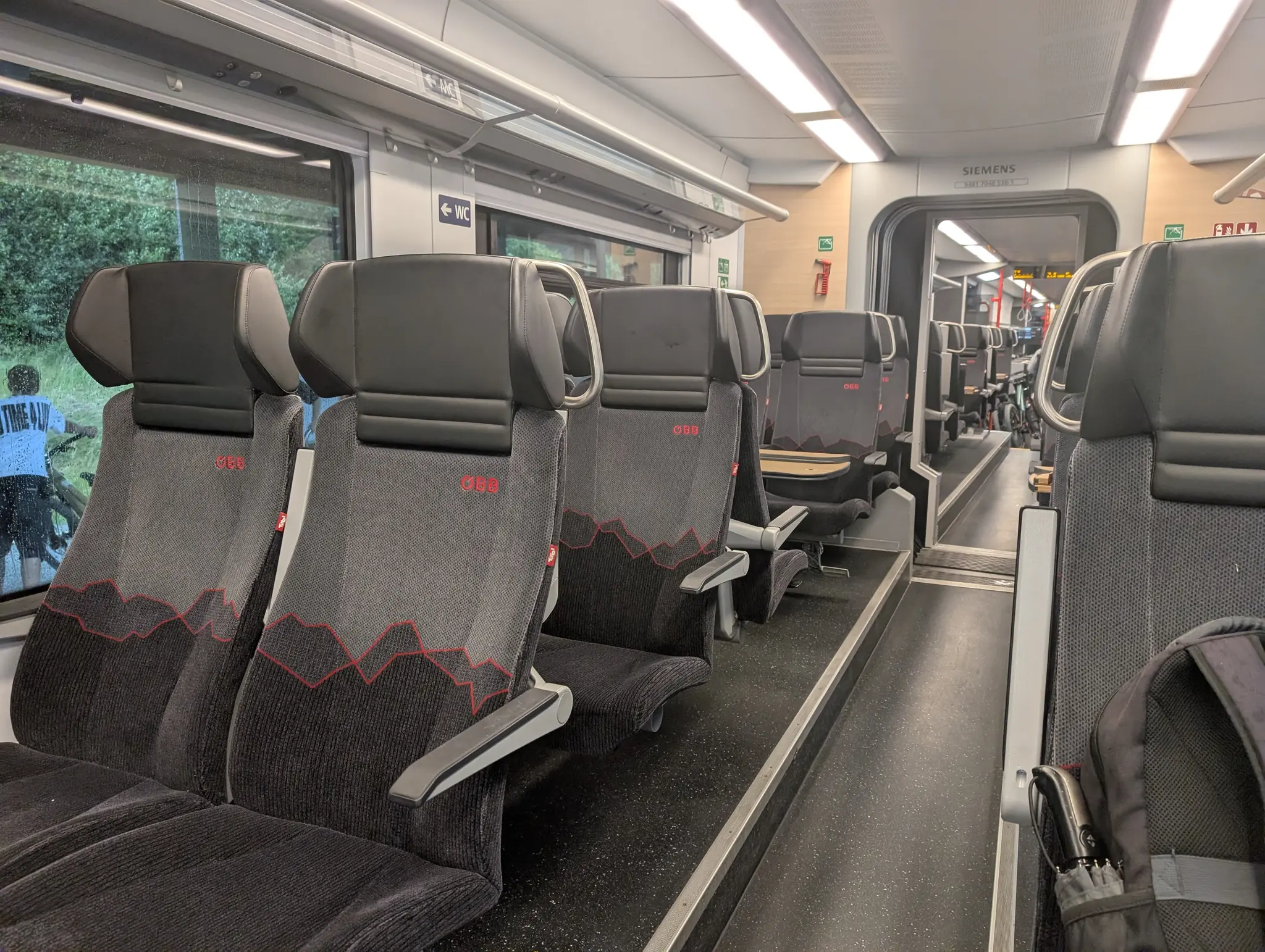Sitze in einem Desiro ML mit einem Design mit Bergen. Neben dem ÖBB Logo ist eine kleine Tirol-Marke.