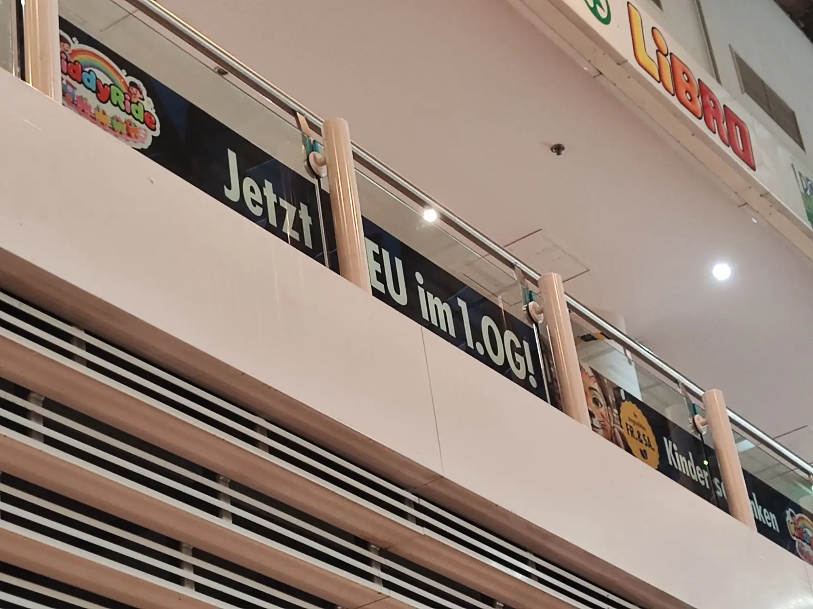 Foto von einem Schild, worauf wegen einer Säule "Jetzt EU im 1. OG" zu lesen ist.